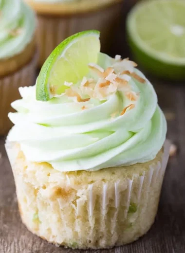 Delicious coconut cupcakes with lime buttercream frosting on a white plate.