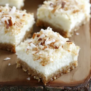 Skinny coconut cheesecake bars topped with shredded coconut and a light crust