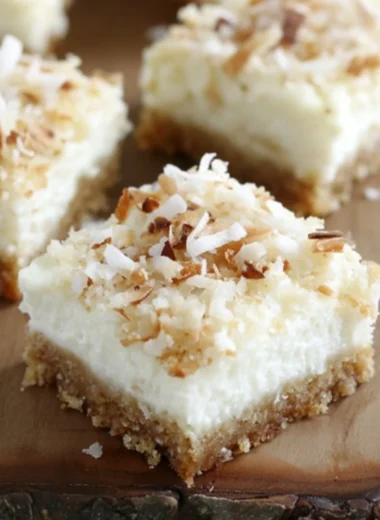 Skinny coconut cheesecake bars topped with shredded coconut and a light crust
