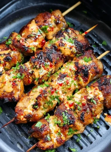 A plate of Air Fryer Bang Bang Chicken Skewers garnished with fresh herbs.