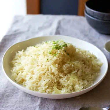 Creamy butter rice served in a bowl, garnished with herbs.