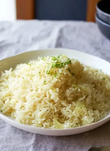 Creamy butter rice served in a bowl, garnished with herbs.