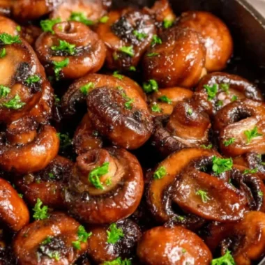 Plate of buttery sautéed mushrooms garnished with herbs