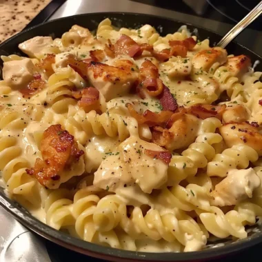 Bowl of creamy Chicken Bacon Ranch Pasta topped with herbs and cheese.