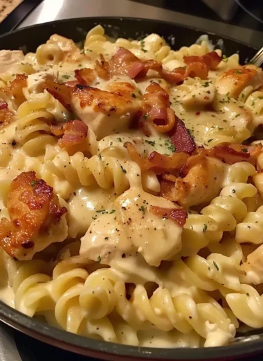 Bowl of creamy Chicken Bacon Ranch Pasta topped with herbs and cheese.