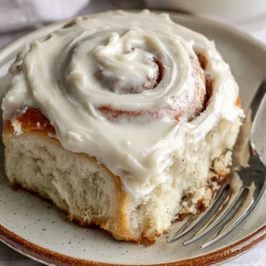 Freshly baked cinnamon rolls topped with icing on a wooden table