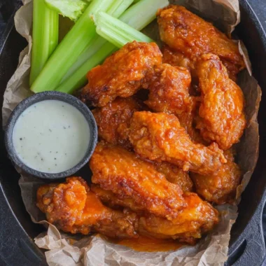 Plate of homemade buffalo wings garnished with celery and dipping sauce