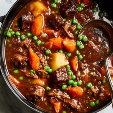 A bowl of homemade beef stew garnished with herbs and vegetables.