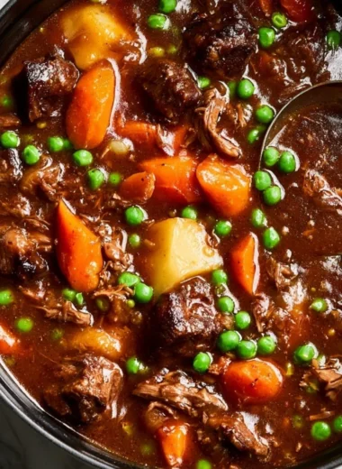 A bowl of homemade beef stew garnished with herbs and vegetables.