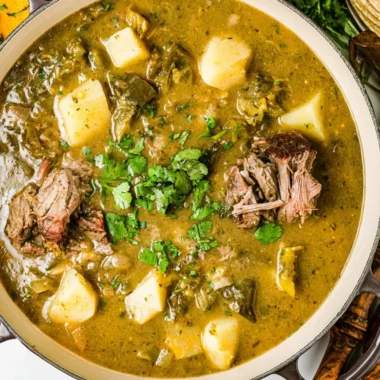 Homemade broth simmering with vegetables and herbs in a pot.