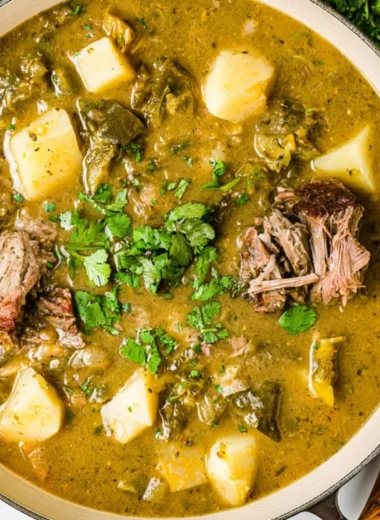 Homemade broth simmering with vegetables and herbs in a pot.