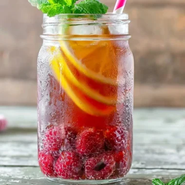 A refreshing glass of Earl Grey Raspberry Iced Tea with fresh raspberries and ice.