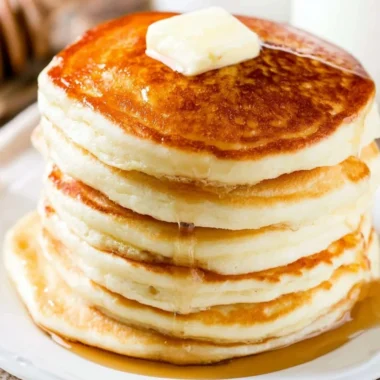 Stack of fluffy pancakes with syrup and berries