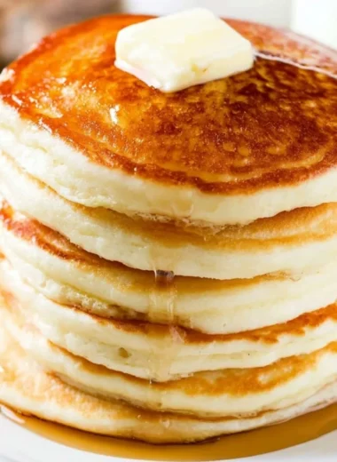 Stack of fluffy pancakes with syrup and berries