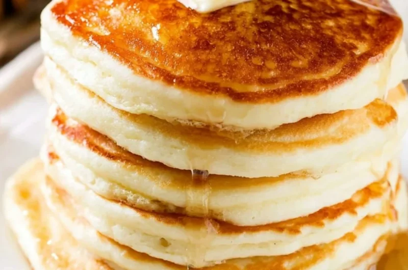 Stack of fluffy pancakes with syrup and berries