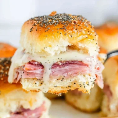 Baked ham and cheese sliders served on a platter.