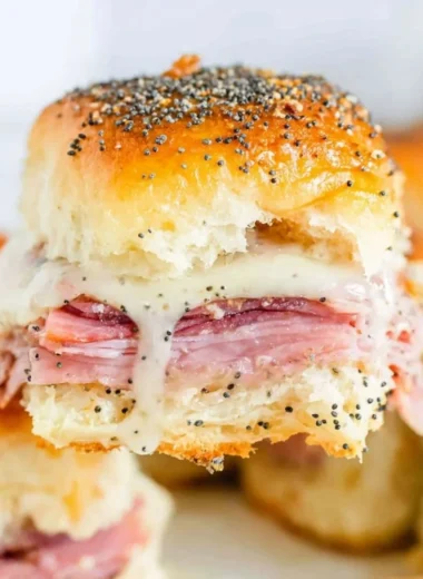 Baked ham and cheese sliders served on a platter.