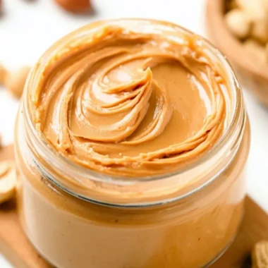 Creamy homemade peanut butter in a jar with a spoon.
