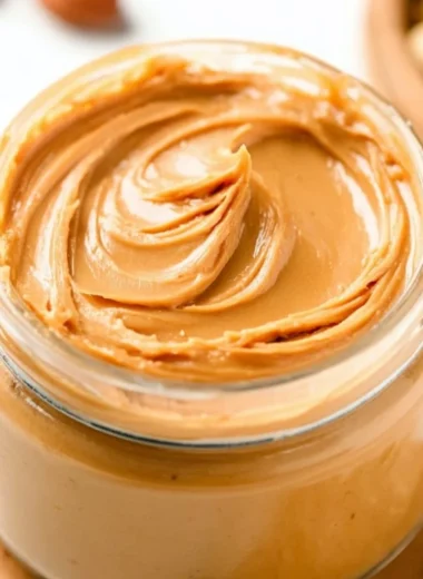 Creamy homemade peanut butter in a jar with a spoon.