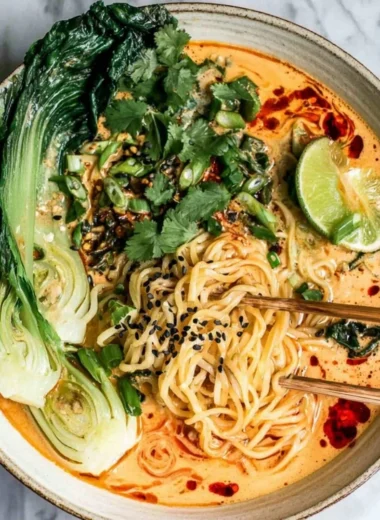 Bowl of quick spicy coconut noodles garnished with herbs and chili flakes
