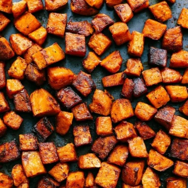 Bowl of roasted sweet potatoes seasoned with herbs and spices.