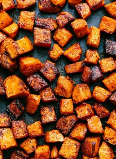 Bowl of roasted sweet potatoes seasoned with herbs and spices.