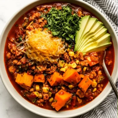 Bowl of Sweet Potato Turkey Chili garnished with herbs and spices.