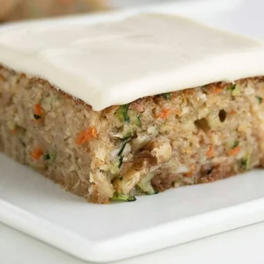 Delicious homemade zucchini bars topped with frosting on a plate
