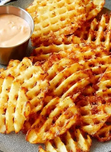Plate of crispy waffle fries served with homemade dipping sauce