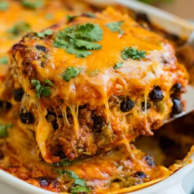 Delicious beef enchilada casserole topped with cheese and garnished with cilantro.