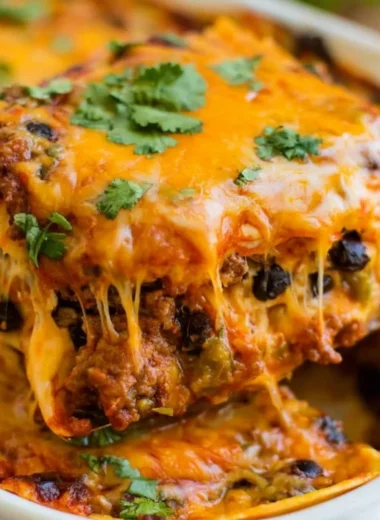 Delicious beef enchilada casserole topped with cheese and garnished with cilantro.