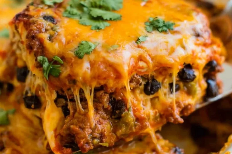 Delicious beef enchilada casserole topped with cheese and garnished with cilantro.