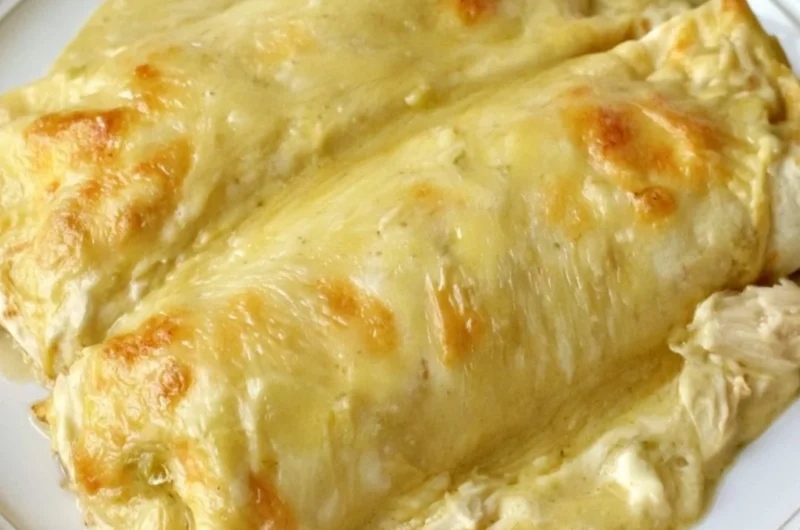 Creamy white chicken enchiladas topped with cheese and herbs