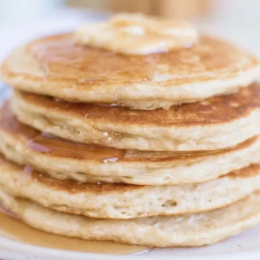 Fluffy sourdough discard pancakes stacked on a plate with syrup.