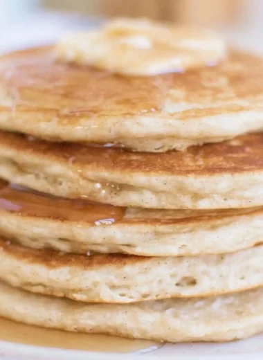 Fluffy sourdough discard pancakes stacked on a plate with syrup.
