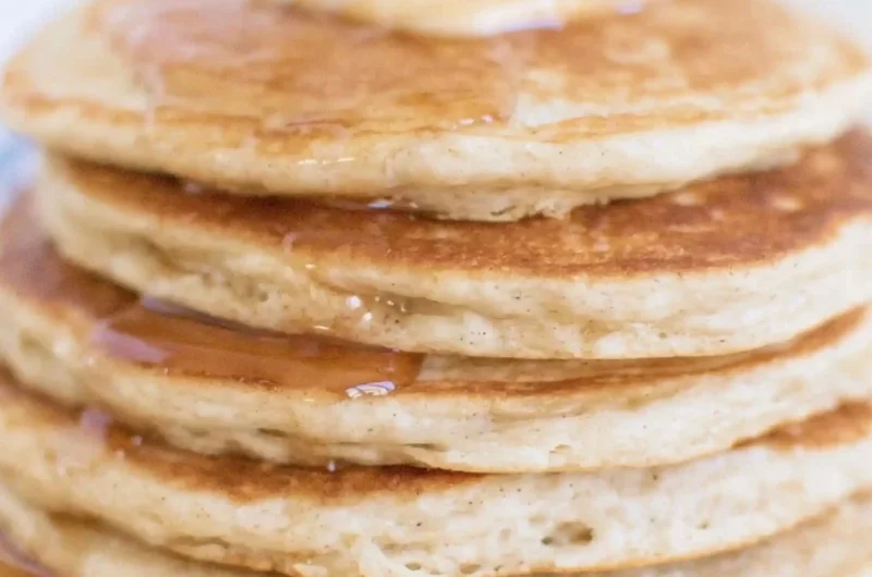 Fluffy sourdough discard pancakes stacked on a plate with syrup.