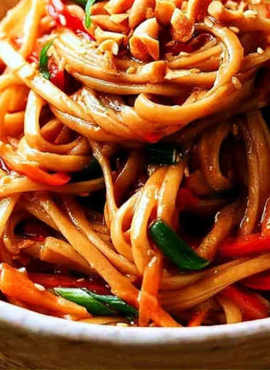 Bowl of easy Thai noodles topped with creamy peanut sauce and fresh vegetables.