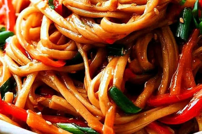 Bowl of easy Thai noodles topped with creamy peanut sauce and fresh vegetables.