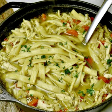 Bowl of homemade chicken noodle soup with fresh herbs and vegetables