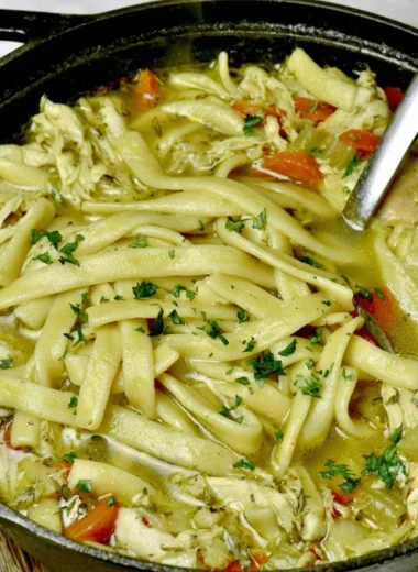 Bowl of homemade chicken noodle soup with fresh herbs and vegetables